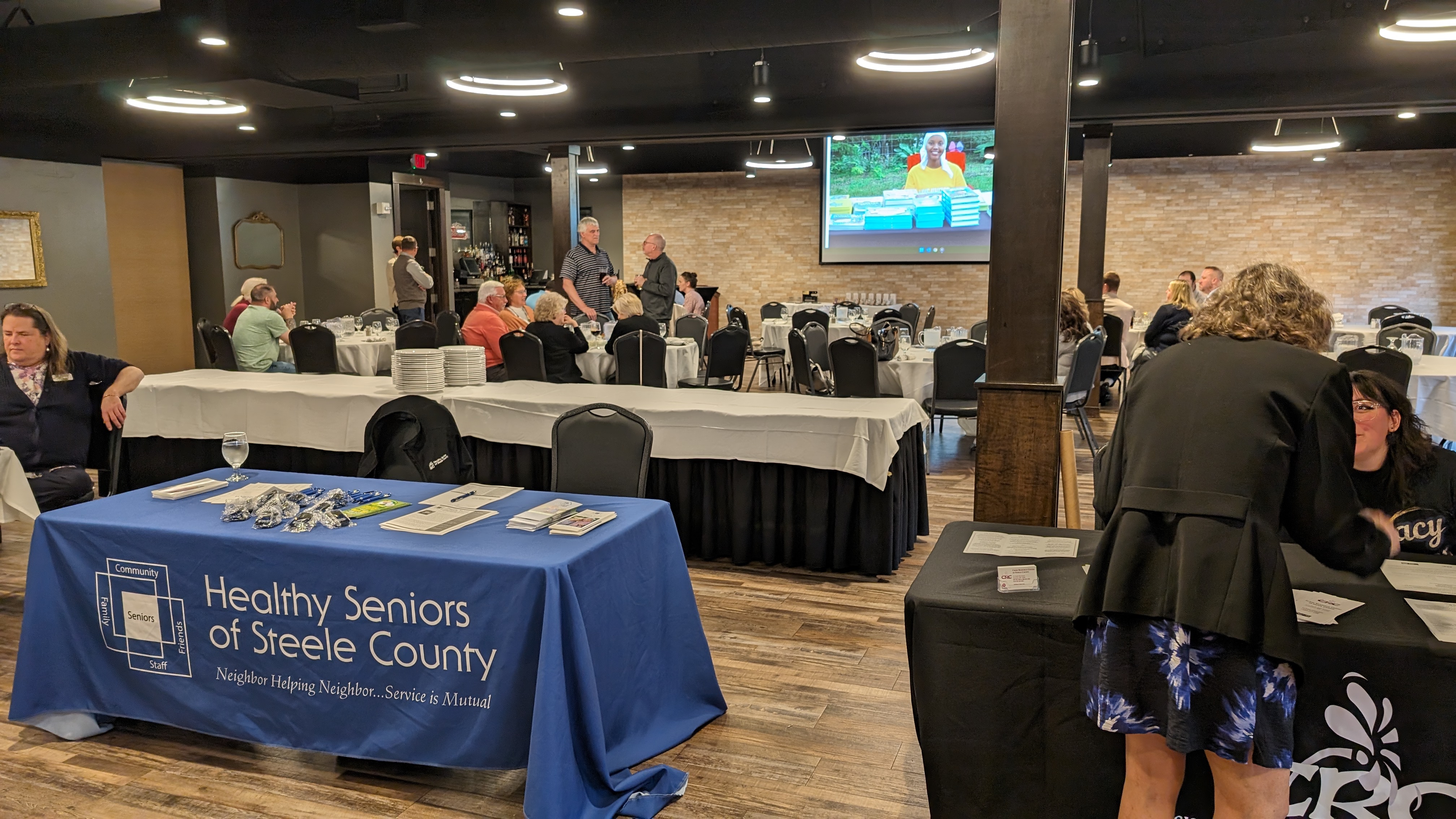 A volunteer handing a punch card to a resident at the bustling Owatonna Recruitment Fair.